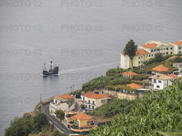 Coastal landscape with a town on a hill, many houses and a passing ship, Madeira, Portugal, Europe