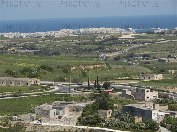 Wide landscape with green fields, small houses and streets, with a town and the sea in the background, the town of mdina on the island of malta with historic houses, colourful balconies, magnificent churches, mdina, Malta, Europe