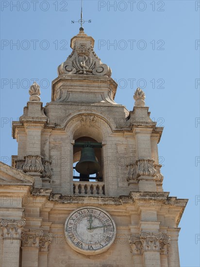 Bell tower of a baroque church with clock under a clear sky, the town of mdina on the island of malta with historic houses, colourful balconies, magnificent churches, mdina, Malta, Europe