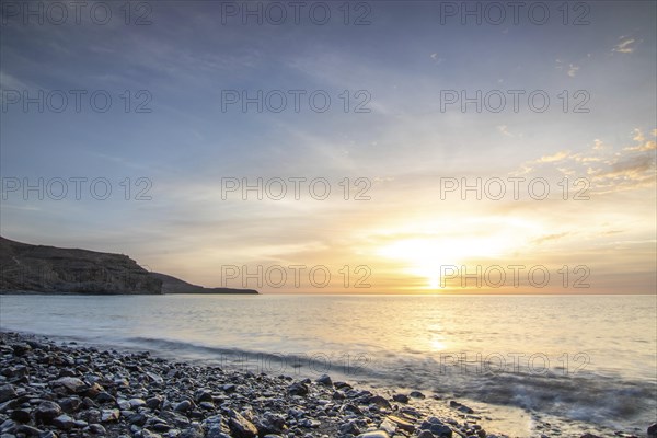 Sunrise with sea view in a lonely bay. rocky coast in warm colours. Landscape with a lava stone beach of Tarajalejo on Fuerteventura, Canary Islands, Spain, Europe
