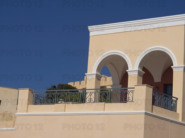 House with elegant arches and balcony in Mediterranean style under a blue sky, The volcanic island of Santorini with blue and white houses and churches, flowers and palm trees on a volcanic island, santorini, greece