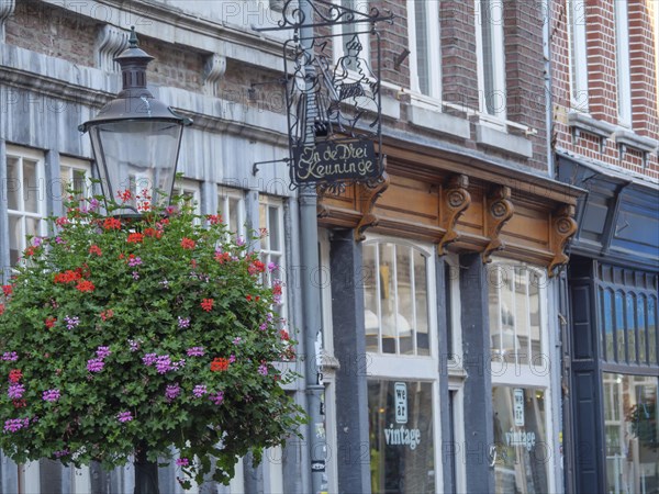 A cobbled street with a vintage-style shop, a street lamp and blooming flowers, Maastricht, Netherlands