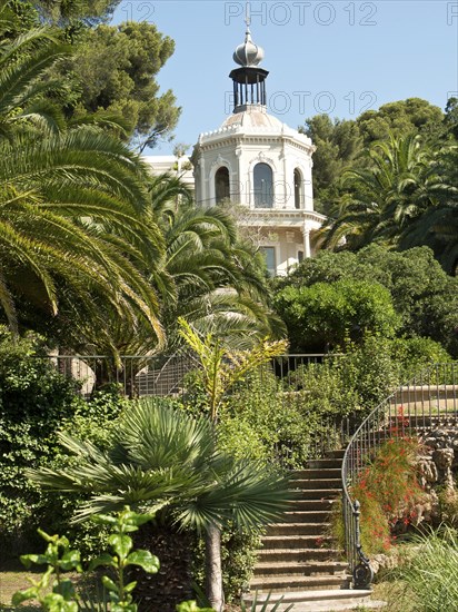 A magnificent villa surrounded by lush gardens and palm trees under a clear sky, la seyne sur mer, france