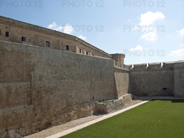Massive stone walls of a fortress with a visible courtyard on a sunny day, the town of mdina on the island of malta with historic houses, colourful balconies, magnificent churches, mdina, Malta, Europe