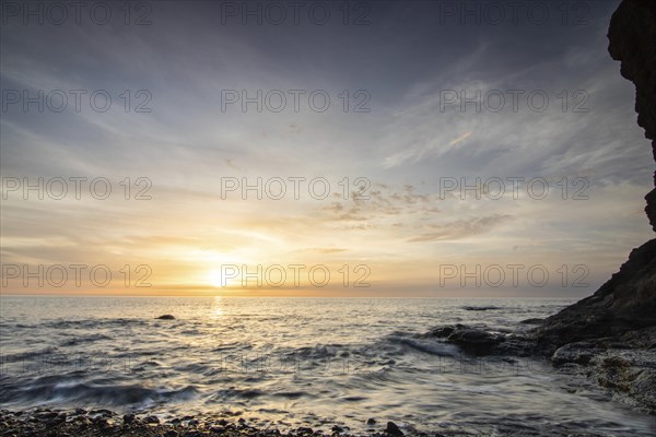 Sunrise with sea view in a lonely bay. rocky coast in warm colours. Landscape with a lava stone beach of Tarajalejo on Fuerteventura, Canary Islands, Spain, Europe
