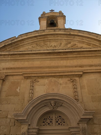 Facade of a historic church with an ornate bell tower under a clear blue sky, the town of mdina on the island of malta with historic houses, colourful balconies, magnificent churches, mdina, Malta, Europe