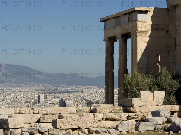 An ancient temple with a view of the modern city and surrounding mountains, Ancient buildings with columns and trees on the Acropolis in Athens against a blue sky, athens, greece