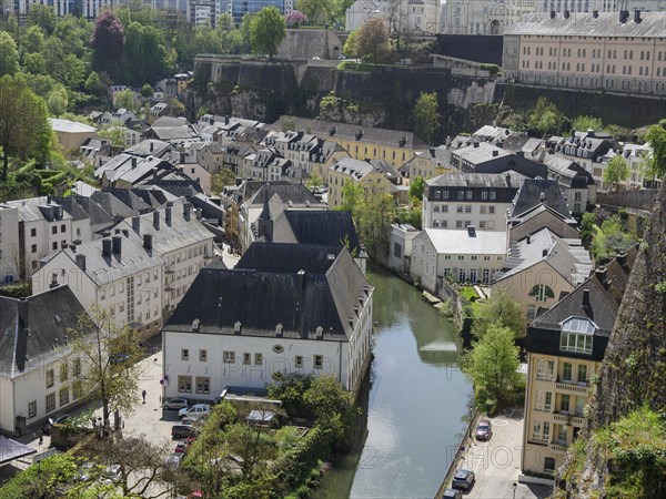 Historic city view with a river, surrounded by old buildings and a bridge, surrounded by lush greenery, view of a historic neighbourhood of a large city by the sea with lots of greenery and old churches, Luxembourg, Europe