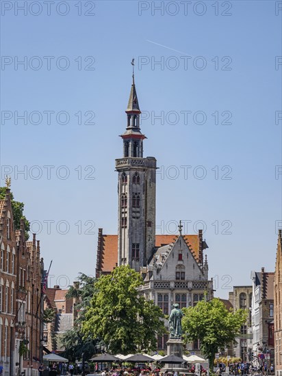 Historic building on the canal in Bruges with a cafe and blue sky on a sunny day, historic houses and churches with towers on a river in Belgium, Bruges, Belgium, Europe