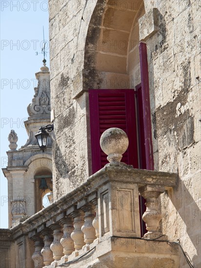 Close-up of historic architecture with red shutters and church tower in the background, the town of mdina on the island of malta with historic houses, colourful balconies, magnificent churches, mdina, Malta, Europe