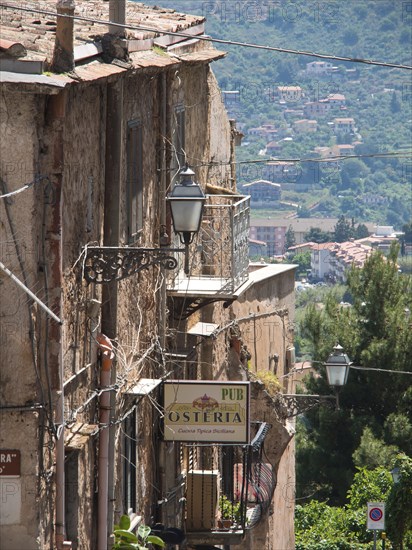 Narrow tram in the old town, lamps and signs for a restaurant, nature and mountains in the background, palermo in sicily with an impressive cathedral, monuments and old houses with balconies, palm trees and flowers in italy, palermo, sicily