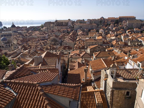 View over the terracotta roofs of a historic city by the sea, sunny atmosphere, the old town of Dubrovnik with historic houses, churches, red roofs and fortress walls, dubrovnik, coratia