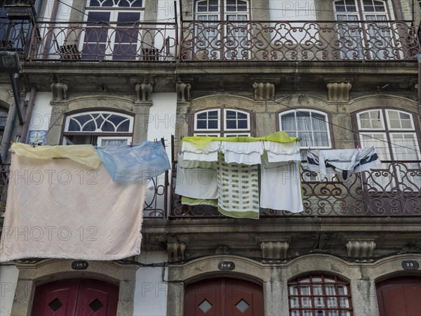 Close-up of balconies with hanging laundry and stone decorations on a historic building, old houses in the historic centre of Porto on the Douro, Porto, portugal
