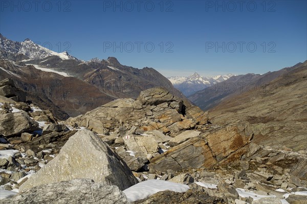 Rugged, snow-covered mountain landscape with occasional wide mountain ranges under a clear blue sky, bare mountain peaks with blue sky, saas fee, switzerland