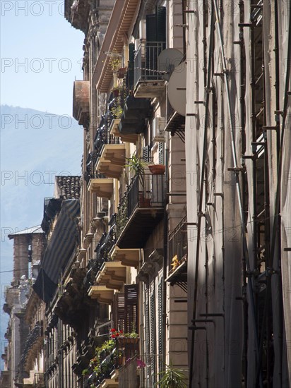 View of narrow streets with balconies and historic buildings in a mediterranean old town, palermo in sicily with an impressive cathedral, monuments and old houses with balconies, palm trees and flowers in italy, palermo, sicily