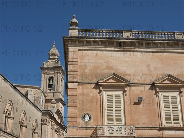 Old buildings with ornate facades and a bell tower against a blue sky, the town of mdina on the island of malta with historic houses, colourful balconies, magnificent churches, mdina, Malta, Europe