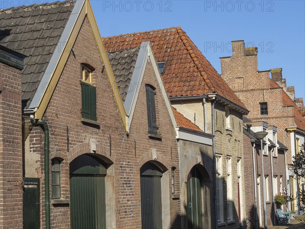 Historic terraced houses with red tiled roofs under a clear blue sky, red brick houses and churches in the Netherlands, Doesburg, Netherlands