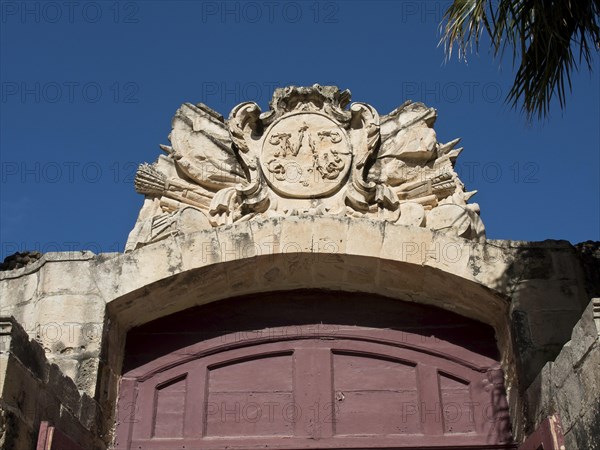 Detailed decorated archway with a coat of arms showing historical motifs under a clear blue sky, the town of mdina on the island of malta with historic houses, colourful balconies, magnificent churches, mdina, Malta, Europe