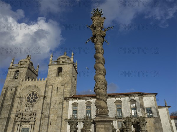 Gothic cathedral with a spiral column in the foreground under a clear blue sky, old houses in the historic centre of Porto on the Douro, Porto, portugal