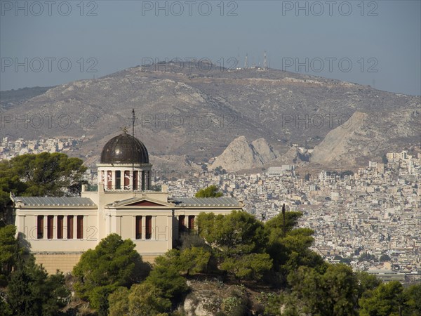Historic building with a dome on a hill surrounded by trees and urban landscape, Ancient building with columns and trees on the Acropolis in Athens against a blue sky, athens, greece