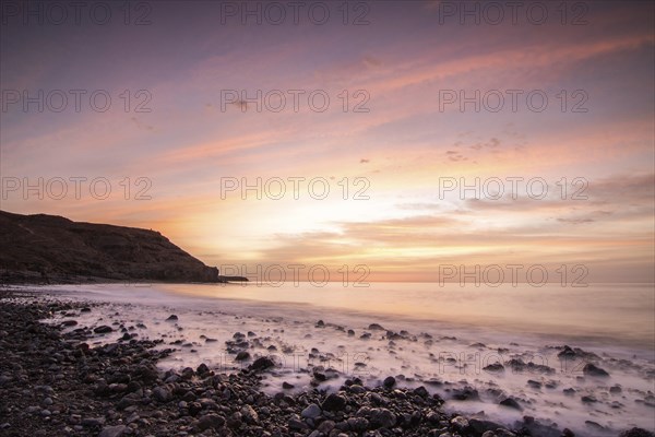 Sunrise with sea view in a lonely bay. rocky coast in warm colours. Landscape with a lava stone beach of Tarajalejo on Fuerteventura, Canary Islands, Spain, Europe