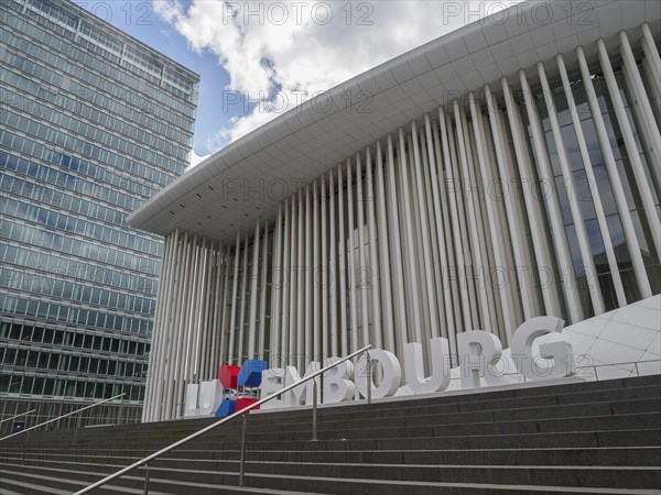 Modern building in Luxembourg with striking columns and glass facade, partly cloudy, modern buildings with trees and glass facades, luxembourg