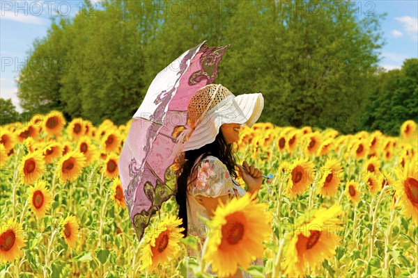Young woman with a parasol in a field of sunflowers
