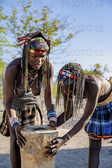 Hakaona woman repairing a drum, in the morning light, Angolan tribe of the Hakaona, near Opuwo, Kunene, Namibia, Africa