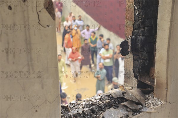 View through a burnt window showing people outdoors amidst debris and destruction, Encounter, Pulwama, Jammu and Kashmir, India, Asia