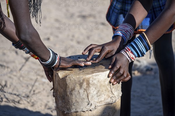 Hakaona woman repairing a drum, detail with hands, in the morning light, Angolan tribe of the Hakaona, near Opuwo, Kunene, Namibia, Africa