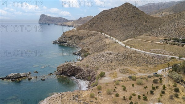 Aerial view from elevated position on small hidden beach Loutra Beach in foreground below, right road highway above south coast of Crete on Libyan Sea Mediterranean, in background Cape Leontas called the Lion, Loutra, Lentas, Crete, Greece, Europe
