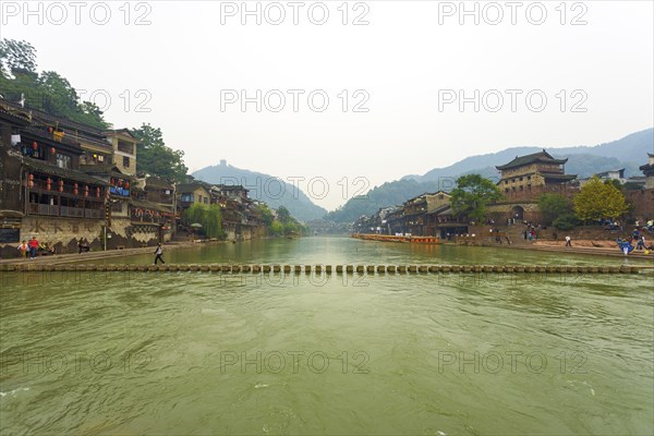 Fenghuang, China, September 10, 2007: A stepping stone bridge spans the Tuojiang River which cuts through the center of the beautiful traditional village and tourist destination of Fenghuang, Asia