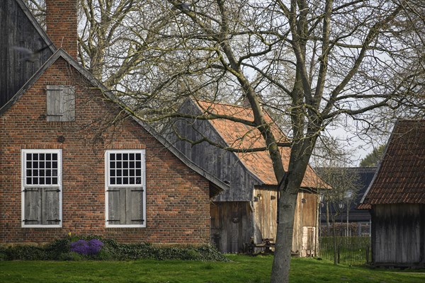 Old brick farmhouse with wooden doors and windows, surrounded by trees and a rural setting, Vreden, North Rhine-Westphalia, Germany, Europe