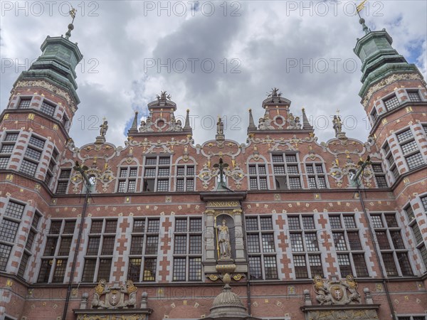 A magnificently decorated historic building with statues and a cloudy sky, Gdansk, Poland, Europe