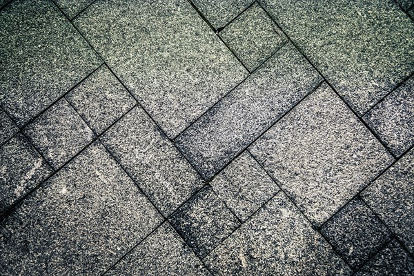 Gray concrete tiles arranged in a geometric pattern creating a rough and textured surface, background image