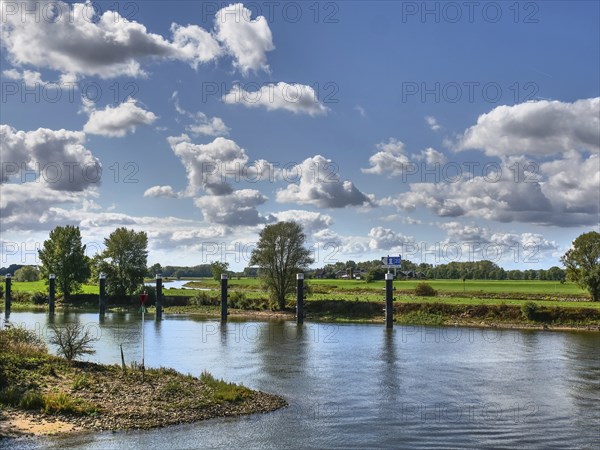 River landscape with green meadows and trees in the background, under a sky full of white clouds, Doesburg, Gelderland, Netherlands