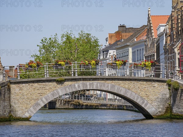 Stone bridge over a canal, decorated with flower boxes and historical buildings in the background, Bruges, Flanders, Belgium, Europe