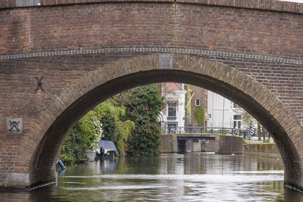 Old stone bridge over a quiet canal flowing through an urban neighbourhood, The Hague, Netherlands