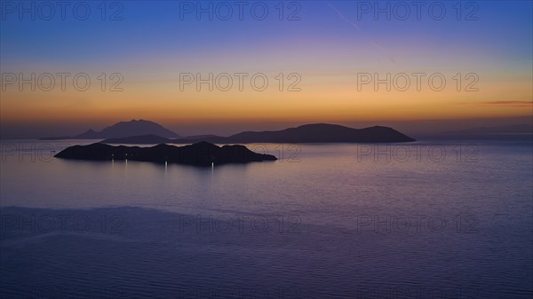 A calm sunset over the sea, the islands in the background surrounded by a gentle colour gradient of blue and orange, Makri Island, Alimia Island, Chalki Island, Kritinia Castle, Kritinia, Rhodes, Dodecanese, Greek Islands, Greece, Europe
