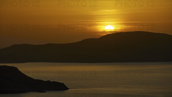 A peaceful seascape at sunset, hills in the background, illuminated by warm golden light, Makri Island, Alimia Island, Kritinia Castle, St John's Castle, Kritinia, Rhodes, Dodecanese, Greek Islands, Greece, Europe