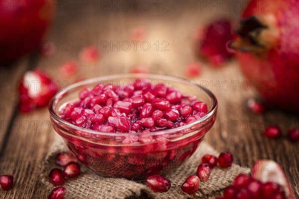 Portion of healthy preserved Pomegranate seeds on an old wooden table (selective focus, close-up shot)
