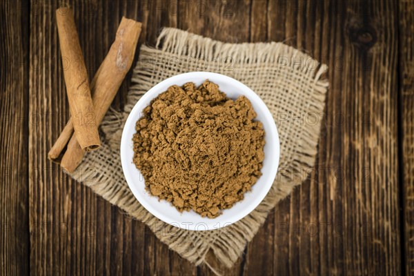 Cinnamon Powder as high detailed close-up shot on a vintage wooden table (selective focus)