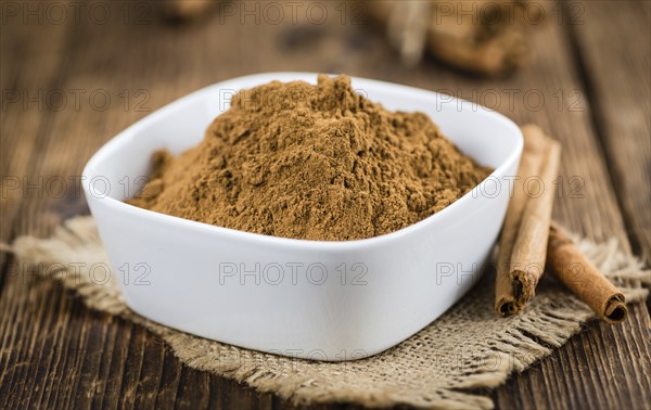Cinnamon Powder as high detailed close-up shot on a vintage wooden table (selective focus)