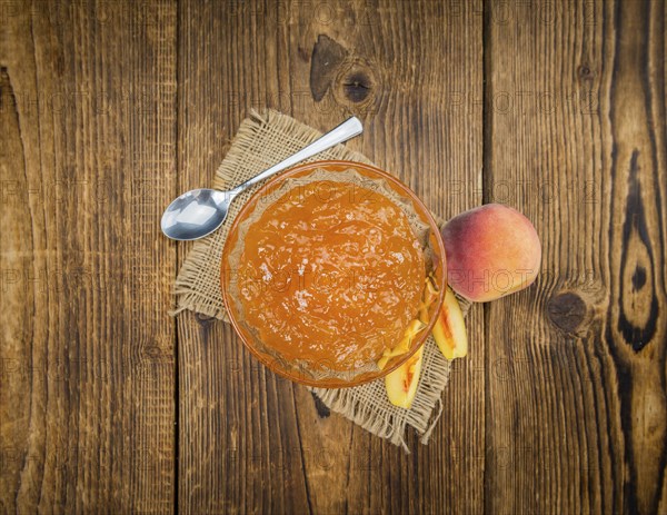 Peach Jam on an old wooden table as detailed close-up shot, selective focus