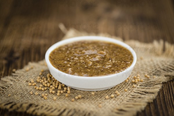 Mustard (sweet) on rustic wooden background (close-up shot)