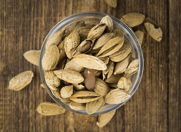 Roasted and salted Almonds (with shell) on a vintage background (close-up shot)