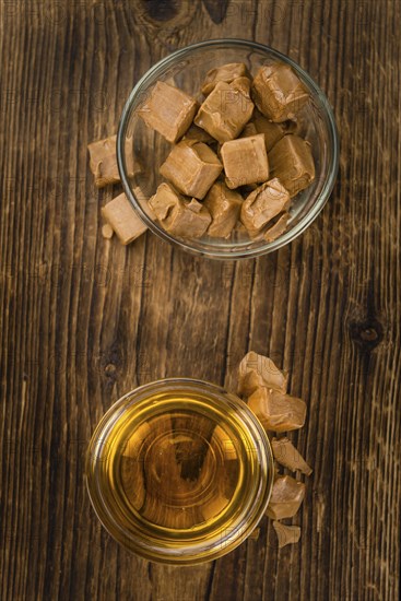Syrup (Caramel taste) on an old wooden table as detailed close-up shot (selective focus)