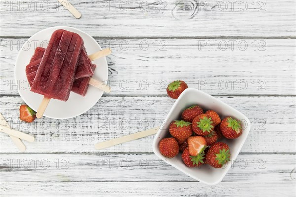 Homemade Strawberry Popsicles (close-up shot, selective focus) on vintage background