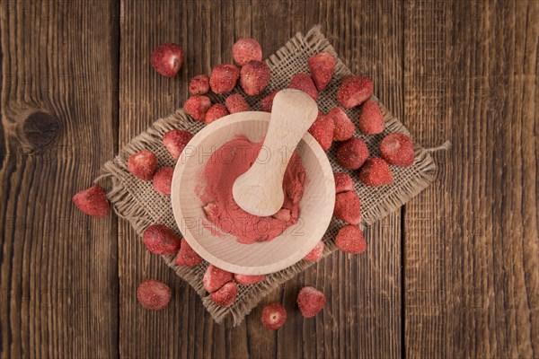 Strawberry powder as high detailed close-up shot on a vintage wooden table, selective focus