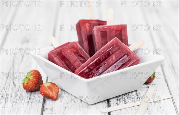 Homemade Strawberry Popsicles (close-up shot, selective focus) on vintage background